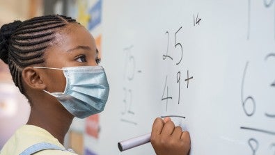 child in mask at dry erase board